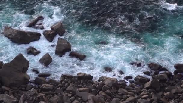 Ondas quebrando rochas escuras erosivas de basalto perto da costa . — Vídeo de Stock