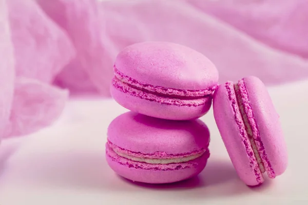 Delicious french dessert. Three gentle soft pastel pink purple cakes  macaron or macaroon on airy fabric,