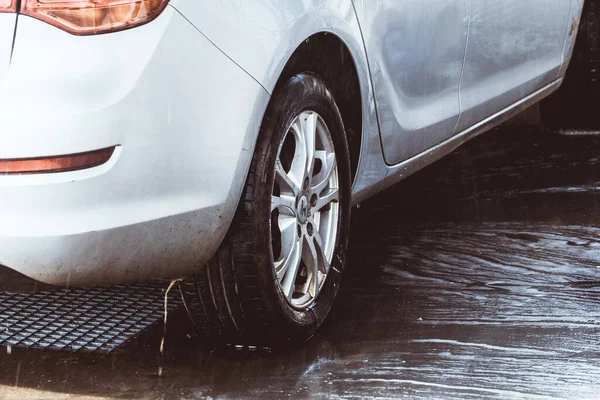 Araba oto yıkamada, adam köpük yıkama makinesinde. Araba yıkama. İstasyonda çamaşır makinesi var. Seçici odak.