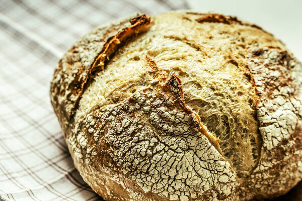 Fresh baked loaf of bread. Rustic sourdough bread on a napkin. Close up. Selective focus.