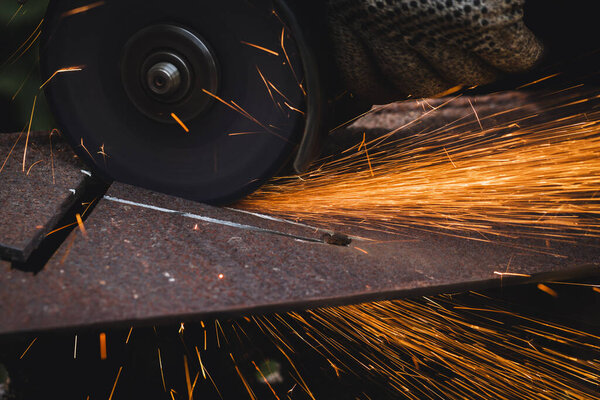 grinding cutting metal sheet with angle grinder machine and sparks, Close up.