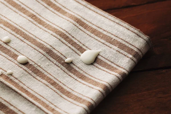 Drops of milk on a linen tablecloth on a wooden background.Still life Royalty Free Stock Images