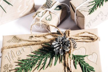 Beyaz arka planda çam kozalakları ve dallarla süslenmiş hediye kutusuyla Noel hediyeleri, tatil hazırlıkları. Seçici odak