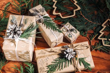 Noel arkaplanı, el yapımı hediye kutuları, ip ve çam kozalaklı süslemeler ve ahşap arka planda dallar. Tatil hazırlığı. El yapımı. Seçici odak.