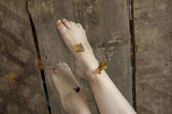 Beautiful legs raised up. Butterflies are sitting on their feet. Lightness of legs. — Stock Photo, Image