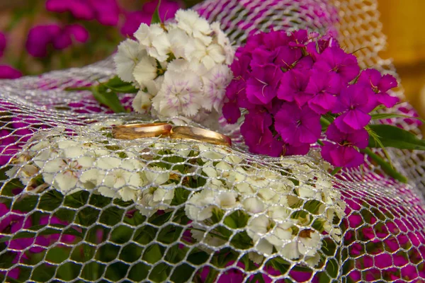 Alyanslar ızgara üzerinde yatıyor. Alyanslar karanfil lerin çiçekleri üzerinde yatıyor. düğün töreni için hazırlık. — Stok fotoğraf
