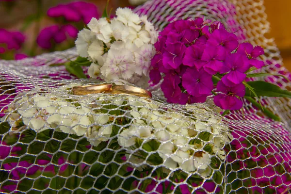 Alyanslar ızgara üzerinde yatıyor. Alyanslar karanfil lerin çiçekleri üzerinde yatıyor. düğün töreni için hazırlık. — Stok fotoğraf