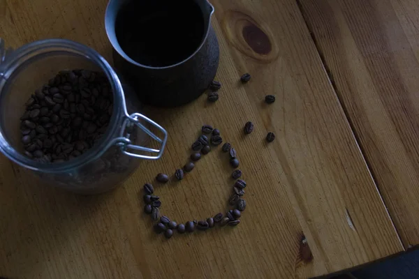 ガラス瓶の中のコーヒーは木製のテーブルの上に立っている。コーヒー豆の心臓部. — ストック写真