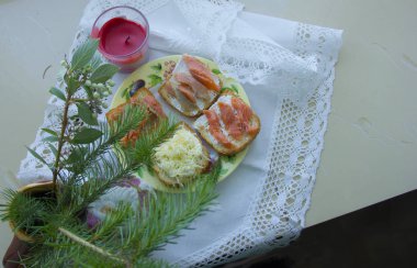 Noel atıştırması. Sandviçlerin yanında hafif bir köknar ağacı ve kırmızı bir mum