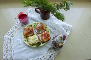 sandviç ile bir tabak yanında dantel ile beyaz bir peçeten in merkezinde bir mum ve Noel Baba heykelcik ile bir mum çubuğu