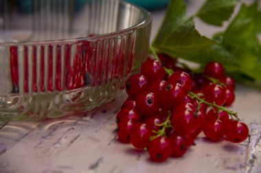 Taze toplayıp kırmızı kuş üzümü ve pembe bir bankta yaprakları Kase