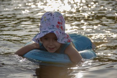 küçük kız bir panama ve bir mayo nehir suyunda bir lastik halka üzerinde yüzer