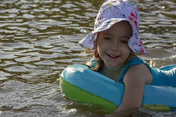 küçük kız bir panama ve bir mayo nehir suyunda bir lastik halka üzerinde yüzer
