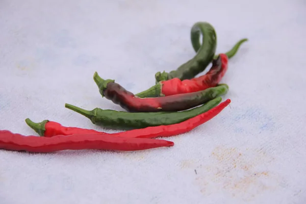 Varm peppar röd och grön på en vit bakgrund. Varmkryddning — Stockfoto