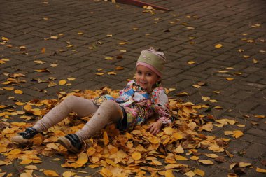 Sarı yaprakların üzerinde yatan kız. sonbahar eğlencesi