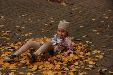 Sarı yaprakların üzerinde yatan kız. sonbahar eğlencesi