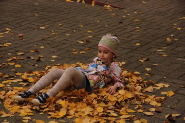 Sarı yaprakların üzerinde yatan kız. sonbahar eğlencesi