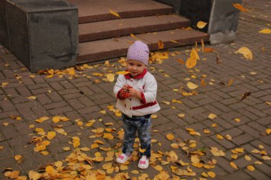 Çocuk, yukarıdan düşen sarı yaprakların üzerinde duruyor.