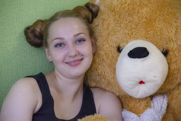 Chica con un oso de peluche en la cama en la habitación — Foto de Stock