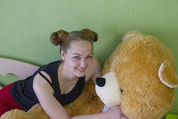 Chica con un oso de peluche en la cama en la habitación — Foto de Stock