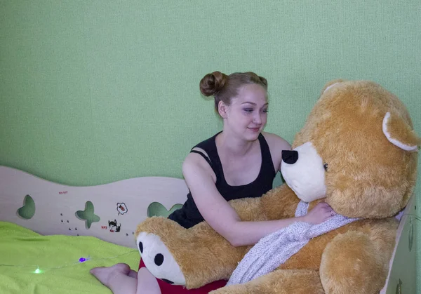 Girl with a teddy bear on the bed in the room — Stock Photo, Image