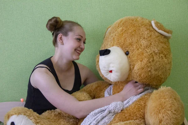 Chica con un oso de peluche en la cama en la habitación — Foto de Stock