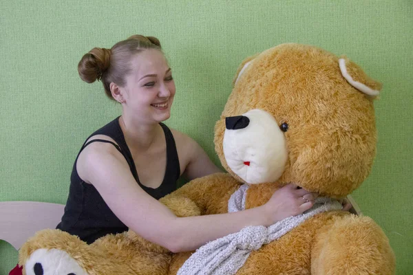 Chica con un oso de peluche en la cama en la habitación — Foto de Stock