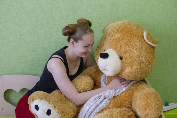 Chica con un oso de peluche en la cama en la habitación — Foto de Stock