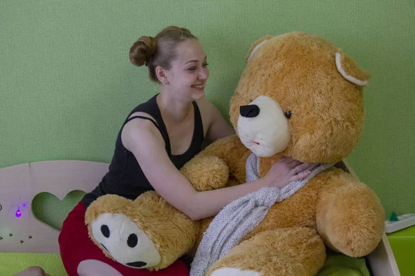 Chica con un oso de peluche en la cama en la habitación — Foto de Stock