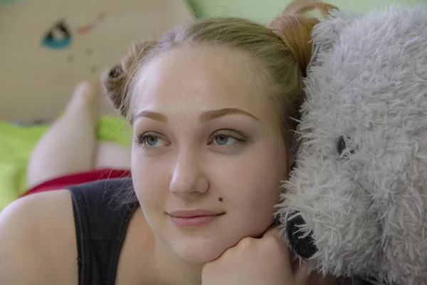 Chica con un oso de peluche en la cama en la habitación —  Fotos de Stock