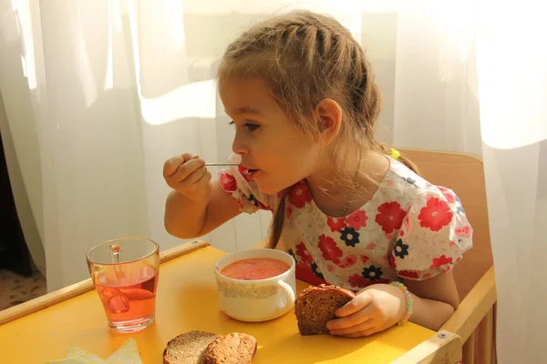 Ragazza prescolare mangia deliziosamente in un accogliente ristorante o scuola materna — Foto Stock