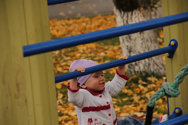 Милая счастливая девочка, ребенок веселится на качелях на детской площадке — стоковое фото