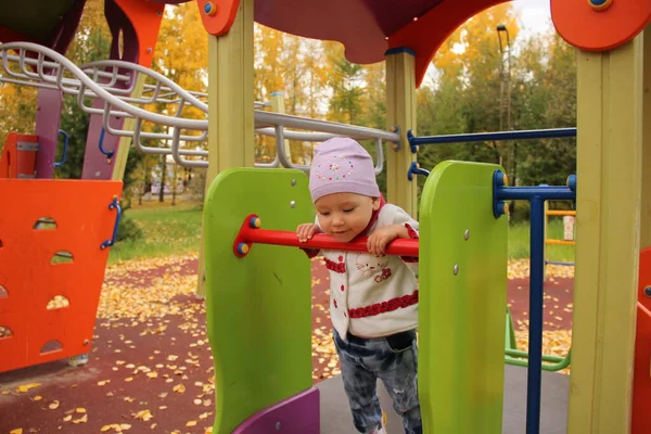 Милая счастливая девочка, ребенок веселится на качелях на детской площадке — стоковое фото