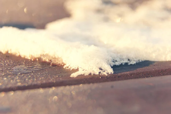 a pile of snow on a wooden surface shines in the sun. on a wooden surface. frosty Siberia