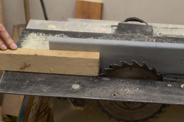 Yaşlı bir marangoz makinenin çubuğuyla ilgilenir. Erkekler araçlarla çalışır.