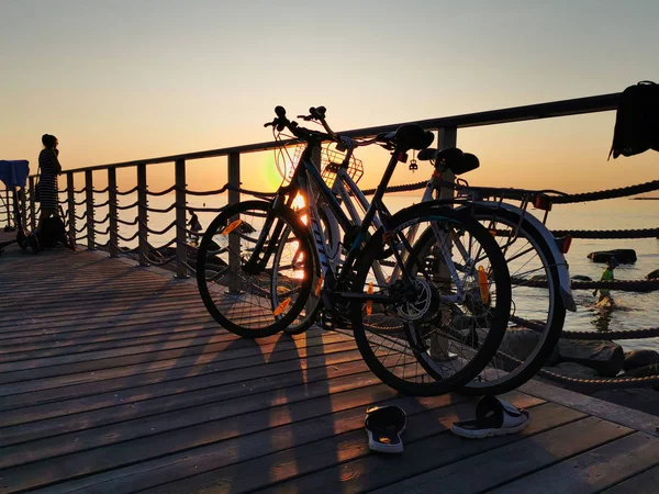 Tallinn, Estonya - 09.2019. denizde gün batımına karşı bir Bisiklet siluetleri. Yetişkinler ve çocuklar Bisiklet