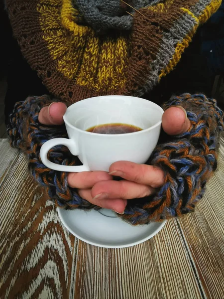 Υπέροχα Γυναικεία χέρια που κρατούν ένα λευκό φλιτζάνι ζεστό καφέ. Ένα κορίτσι σε ένα άνετο ζεστό πλεκτό πουλόβερ κρατώντας ένα φλιτζάνι ζεστό καφέ Εικόνα Αρχείου