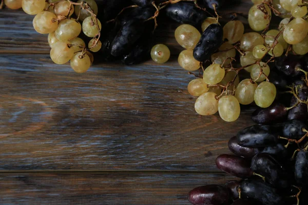 Racimo de uvas jugosas blancas y azules oscuras en una tabla de madera —  Fotos de Stock