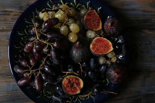 Frutas de otoño recién recogidas. Uvas e higos blancos y negros sobre mesa de madera oscura —  Fotos de Stock