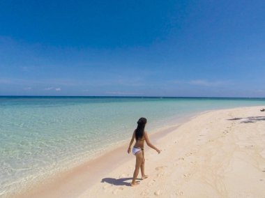 Balabac, Palawan, Filipinler Pink Adası'nda açık mavi gökyüzü ile beyaz plaj ve turkuaz su üzerinde yürüyüş Kız
