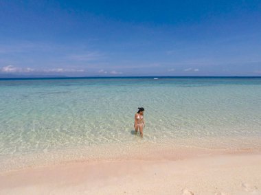 Balabac, Palawan, Filipinler Pink Adası'nda açık mavi gökyüzü ile beyaz plaj ve turkuaz su üzerinde yürüyüş Kız