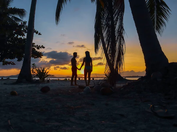 Lovely couple watching sunset with palm trees in Candaraman Island in Balabac Philippines