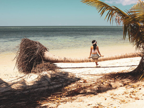 girl sitting on palm tree body like a bench in Onok island in Balabac in Palawan Philippines