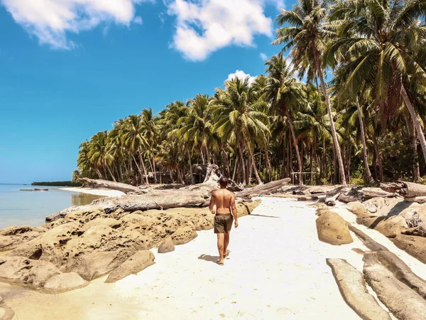白いビーチとターコイズブルーの水の上を歩く男 澄んだ青空とバラバク島のヤシの木の多くは パラワン フィリピン — ストック写真