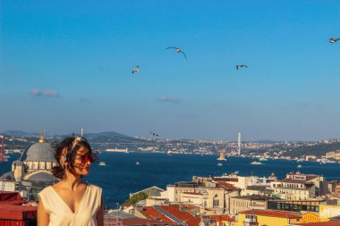 İstanbul'da boğaz arka planı yla çatıda duran Avrasyalı kadın