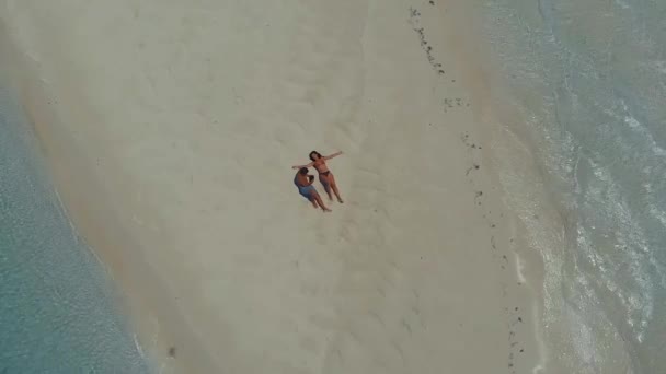 Drone subindo acima do casal deitado no sandbar Mansalangan em Balabac — Vídeo de Stock