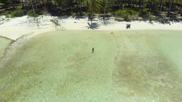 Drone subindo sobre mulher no meio da praia de areia branca na ilha de Candaraman — Vídeo de Stock