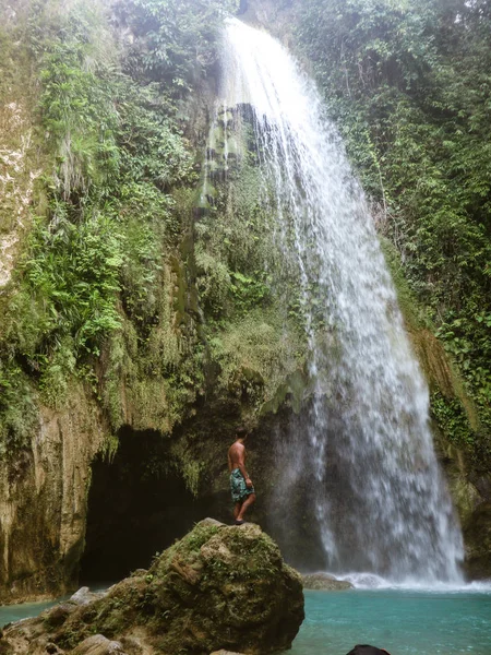 Epic man alone in deep forest waterfall from mountain gorge at hidden tropical jungle in Cebu Island in Philippines