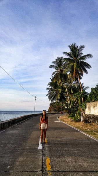 フィリピンのセブ島でヤシの木がたくさんある空の道を一人で歩く女性 — ストック写真