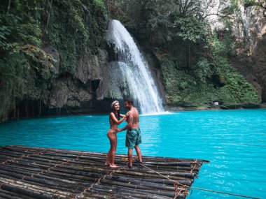 Cebu Adası Kawasan Şelalesi turkuaz su ile şelale önünde bambu sal üzerinde yalnız seyahat çift, Filipinler